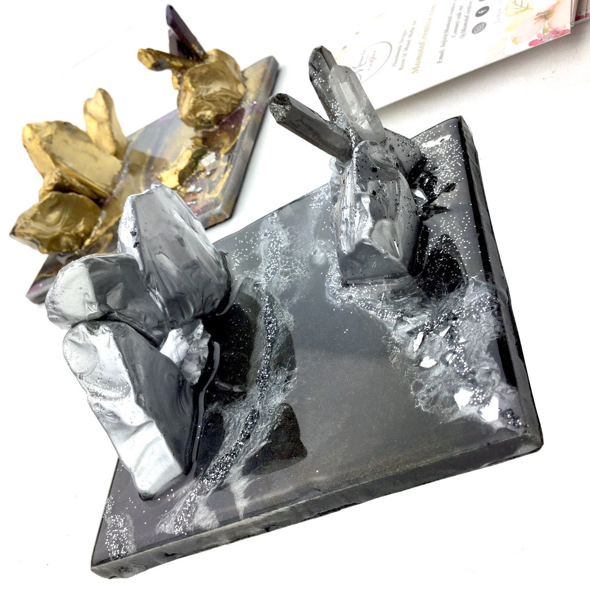 Two geode-inspired resin business card and smartphone holders in purple and gold and black and silver