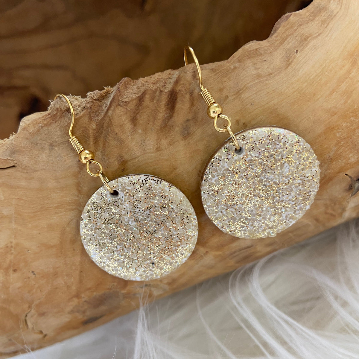 Close-up of round sand-textured resin drop earrings with subtle shimmer