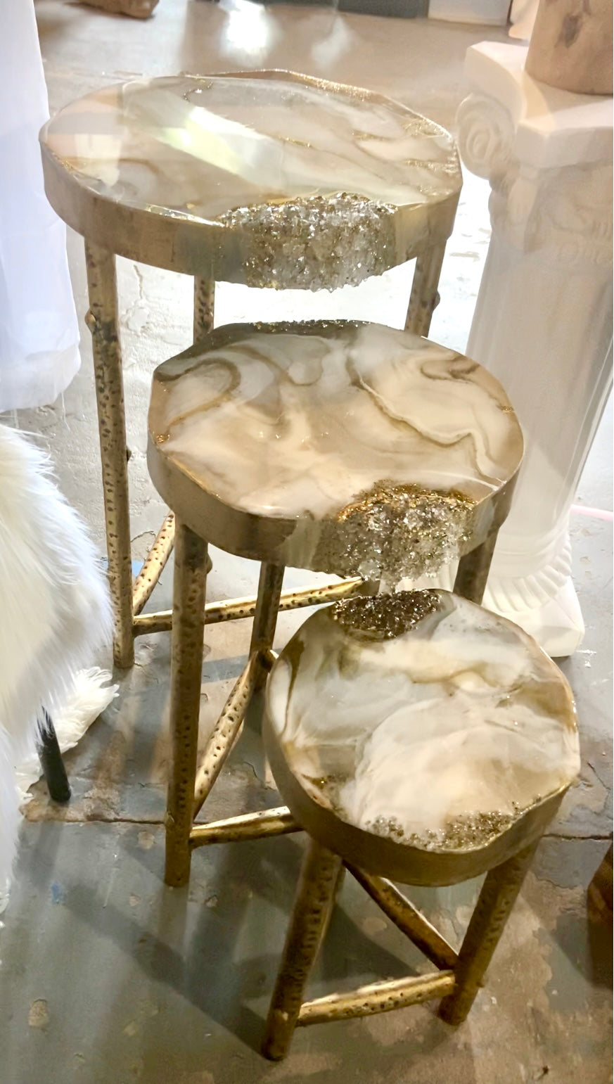 Set of three round nesting tables with gold frames and marble-like tops on a light background