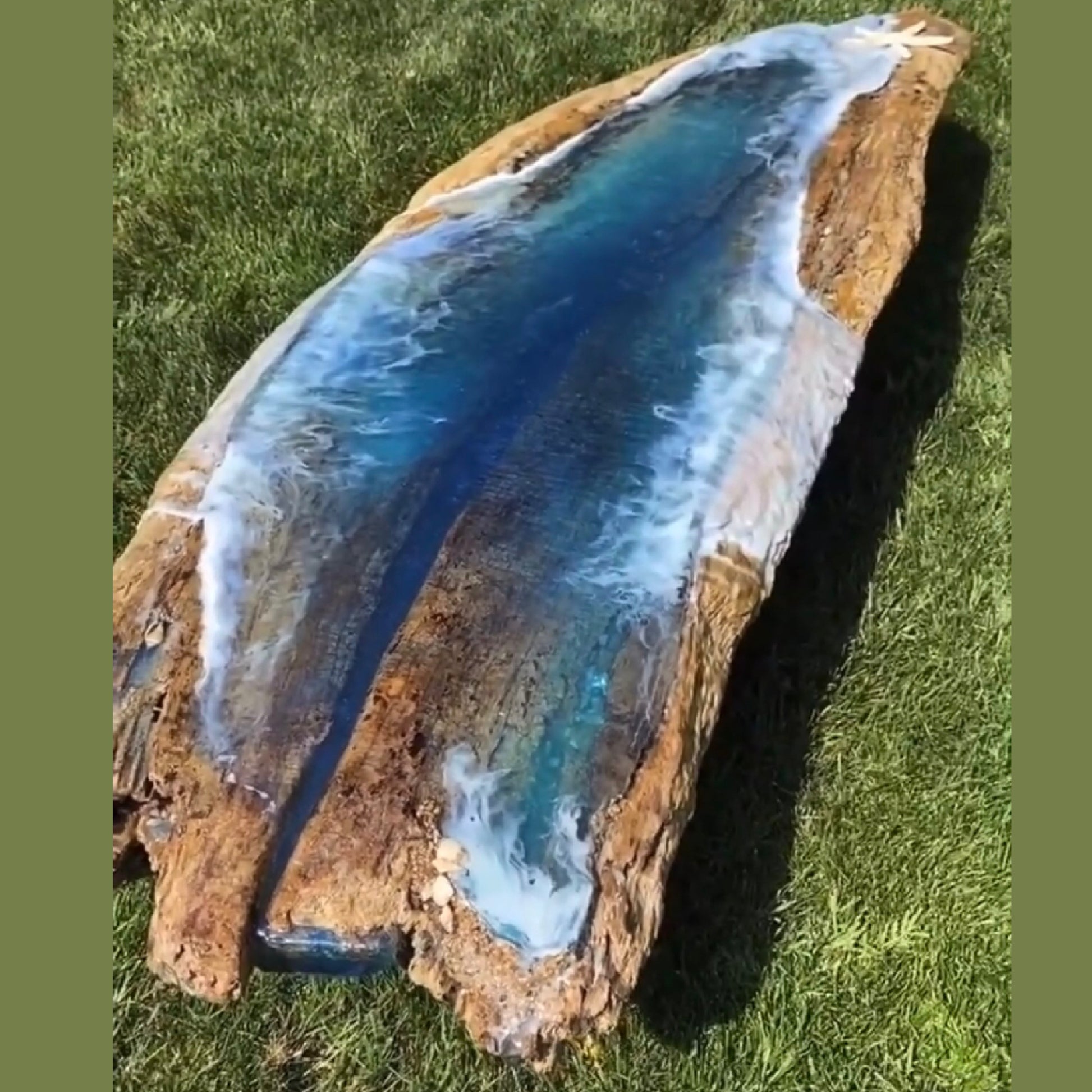 long organic shape table with a beach theme resin art in an grass a outdoor setting