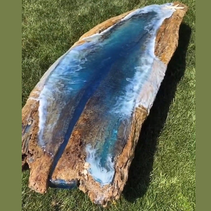 long organic shape table with a beach theme resin art in an grass a outdoor setting